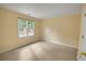 Bedroom with light-yellow walls featuring neutral carpet, a large window, and a double-door closet at 1411 Blackland Trl, Lawrenceville, GA 30043