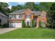 Two-story brick home with a manicured lawn and a two car garage and beautiful, mature trees at 1411 Blackland Trl, Lawrenceville, GA 30043