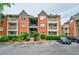 Brick condo building featuring a balcony and reserved parking spaces, surrounded by lush greenery at 4106 Chastain Park Ne Ct, Atlanta, GA 30342