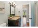 Bathroom vanity with granite countertop, decorative mirror, and view to another room with ceiling fan at 440 Laurian Nw Way, Kennesaw, GA 30144