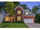 Well-maintained two-story brick home featuring manicured lawn and a two-car garage at twilight at 440 Laurian Nw Way, Kennesaw, GA 30144