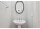 Clean and minimalist powder room features a pedestal sink and oval mirror at 3949 Glenview Club Ln, Duluth, GA 30097