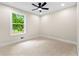 Cozy bedroom with neutral carpet, ceiling fan, and a window view to a landscaped yard at 4043 Chedworth Way, Stone Mountain, GA 30083
