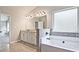 Bathroom with granite countertops, white cabinets, gray tile flooring, and a view of the bathtub and entry at 238 Linford Dr, Locust Grove, GA 30248