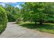 Long concrete driveway leading to a home surrounded by lush greenery and mature trees at 55 Fox Chase, Covington, GA 30016