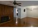 Open living room showcasing hardwood floors, wood paneling, fireplace, ceiling fan and view into the kitchen at 5826 Par Four Ct, Lithonia, GA 30038