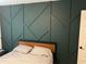 Modern bedroom featuring a bold, decorative green wall and simple, stylish furnishings at 6780 Cedar Glen Rd, Peachtree Corners, GA 30360