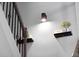 Close up of staircase featuring iron railings and floating shelves, with a modern lighting fixture illuminating the wall at 6780 Cedar Glen Rd, Peachtree Corners, GA 30360
