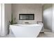 Close-up of the soaking tub, fireplace, modern fixtures, and neutral tile in this modern bathroom at 5160 Howard Rd, Cumming, GA 30040