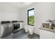 Modern laundry room with stainless steel appliances, neutral decor, and natural light at 5160 Howard Rd, Cumming, GA 30040