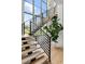Bright modern staircase featuring light wood treads, black metal railings, and large windows offering outdoor views at 5160 Howard Rd, Cumming, GA 30040