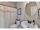 Cozy bathroom featuring a round mirror, toilet, and curtained shower at 1370 Sunnys Halo Dr, Suwanee, GA 30024