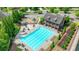 Aerial view of the community pool with a pool house, tables, chairs, umbrellas, playground, and green landscaping at 1370 Sunnys Halo Dr, Suwanee, GA 30024