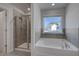 Bathroom featuring a glass-enclosed shower and a luxurious soaking tub under a bright window at 266 Tulip Dr, Covington, GA 30016