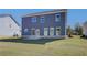View of the backyard shows blue siding, a concrete patio, and well-maintained lawn at 107 St Annes Pl, Covington, GA 30016