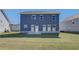 Backyard view of home featuring spacious lawn, brick patio, and blue siding at 107 St Annes Pl, Covington, GA 30016
