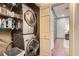 Convenient stacked washer and dryer setup with shelving for storage and an open view to the hallway at 2499 Peachtree Ne Rd # 108, Atlanta, GA 30305