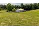 Aerial view of a white barn in a fenced green pasture, surrounded by trees, perfect for equestrian activities at 255 Henson Way, Canton, GA 30115