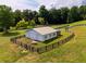 This fenced barn features a metal roof and access doors within a verdant, tree-lined landscape at 255 Henson Way, Canton, GA 30115