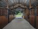 Interior view of the barn featuring multiple stalls and an open design, with a view of a fenced pasture at the end at 255 Henson Way, Canton, GA 30115