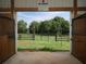 Barn interior showcases an open doorway, providing a view of a lush pasture and a wooden fence at 255 Henson Way, Canton, GA 30115