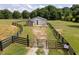Fenced barn with metal roof surrounded by luscious greens, featuring access doors and a gated entrance at 255 Henson Way, Canton, GA 30115