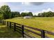 White barn with fenced pasture, surrounded by trees, perfect for enjoying equestrian activities at 255 Henson Way, Canton, GA 30115