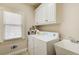 Functional laundry room features washer, dryer, sink, cabinet, and window at 737 Heritage Post Ln, Grayson, GA 30017