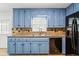 Well-lit kitchen featuring updated blue cabinets, stainless steel appliances, and granite countertops at 3664 Nessa Se Ct, Smyrna, GA 30082