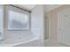 Bathroom featuring large tub with shower, a window, and white tile flooring at 954 Josie Ct, Lawrenceville, GA 30045