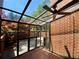 Enclosed sunroom featuring brick walls, brick floors, glass roof and walls, and a ceiling fan at 2259 Pernoshal Ct, Dunwoody, GA 30338
