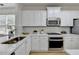 Well-lit kitchen showcasing stainless steel appliances, quartz countertops and bright white cabinets at 3120 Caney Creek Ln, Cumming, GA 30041