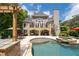 Rear exterior view with a stone pool, hot tub, outdoor kitchen, and spacious patio at 5860 Stoneleigh Dr, Suwanee, GA 30024