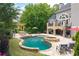 Beautiful backyard pool and patio with spa, outdoor kitchen, and mature trees surrounding the property at 5860 Stoneleigh Dr, Suwanee, GA 30024
