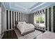Bright bedroom with hardwood floors, a window seat, elegant chandelier, and stylish striped accent wall at 5860 Stoneleigh Dr, Suwanee, GA 30024