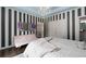 Bedroom with hardwood floors, an elegant chandelier, en-suite bathroom and stylish striped accent wall at 5860 Stoneleigh Dr, Suwanee, GA 30024