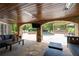 Comfortable covered patio with stone accents, TV, outdoor kitchen, and pool view at 5860 Stoneleigh Dr, Suwanee, GA 30024