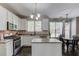 Stylish kitchen with white cabinets, stainless steel appliances, island, and adjacent dining area with modern light fixture at 1370 Stoney Field Place, Lawrenceville, GA 30043
