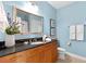 Well-lit bathroom features blue walls, wood cabinets, granite countertops, and a large mirror at 325 E Paces Ferry Rd # 2003, Atlanta, GA 30305