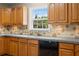 Well-lit kitchen with stone backsplash, wooden cabinets, double sink and black dishwasher at 1903 Lochlomand Se Ln, Smyrna, GA 30080