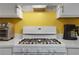Close-up of a white gas stove with matching white cabinets against a bright yellow wall at 3001 Garland Sw Dr, Marietta, GA 30008