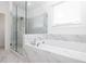 Luxurious bathroom featuring a glass-enclosed shower, a soaking tub, and marble-patterned tile at 711 Dodd N Ln # 166, Buford, GA 30518