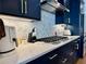 A modern kitchen with stainless steel appliances, white countertops, hexagon backsplash, and navy cabinets at 1320 Stanley Park Dr # 141, Decatur, GA 30033
