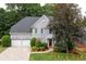 Traditional home showcases a manicured lawn, lush landscaping, light gray exterior, a red front door, and a spacious driveway at 4957 Day Lily Nw Way, Acworth, GA 30102