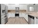 Bright kitchen with white cabinets, stainless steel appliances, tile backsplash, and durable wood-look flooring at 613 Wiley Ct, Canton, GA 30115