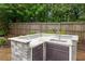 Backyard kitchen featuring granite countertop, sink, and ample storage, all set against a private wooded backdrop at 613 Wiley Ct, Canton, GA 30115