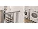 Hall view of staircase adjacent to a laundry room with modern, front-load washer and dryer at 1851 Lacebark Elm Way, Lawrenceville, GA 30045