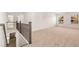 Open loft space with neutral carpet, railing, and view to the kitchen downstairs at 1851 Lacebark Elm Way, Lawrenceville, GA 30045