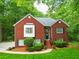 Charming two-story brick home with a well-manicured lawn, lush landscaping, and a welcoming front entrance at 827 Pinehurst Dr, Woodstock, GA 30188