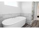 Soaking tub with a modern faucet set against gray-tiled accent wall and dark wood-look flooring at 1781 Jordan Brook Dr, Lawrenceville, GA 30043